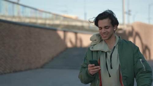Smiling Man Using Smartphone While Walking on Street