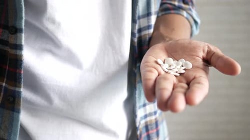 Hand Holding White Pills for Medical Treatment