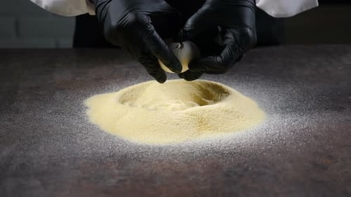 Eggs Being Cracked Into Semolina Flour on Table