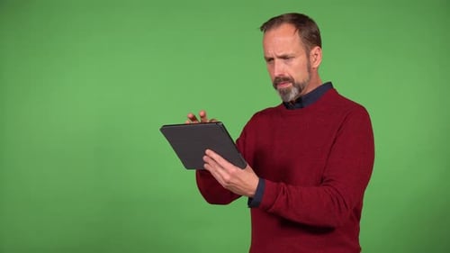 A Middleaged Handsome Caucasian Man Works on a Tablet with a Smile Green Screen Background