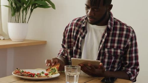 Man eating at home and using tablet