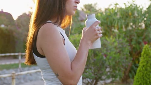 Close up medium shot, young woman drinking water after doing sport