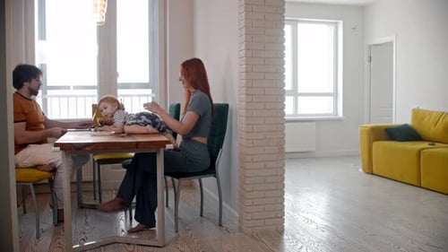 Man Freelancer Works Using His Laptop and His Wife and Baby Sitting on the Other Side of the Table