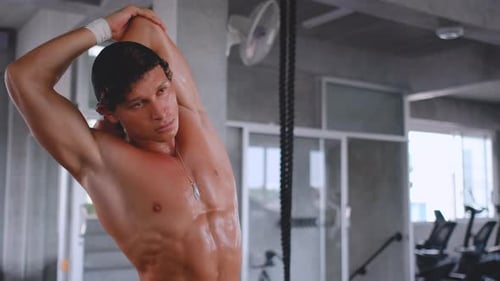 Muscular sport man warm up before exercise with a bit of sweat on body and he stay in gym