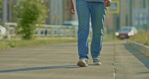 Mann geht in Turnschuhen die Straße entlang
