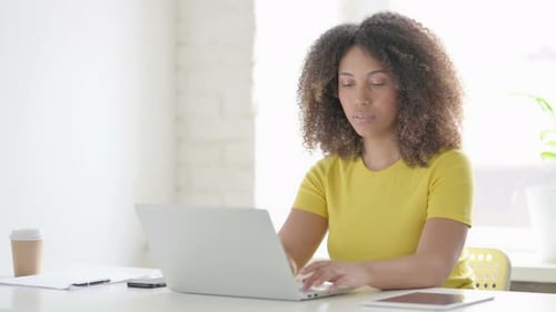 Focused Young Adult Works on Laptop in Office