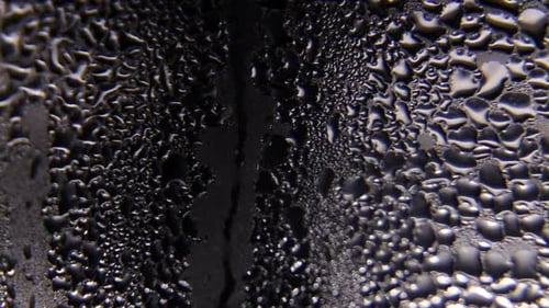 Wassertropfen fließen das Glas hinunter. Regentropfen am Fenster.