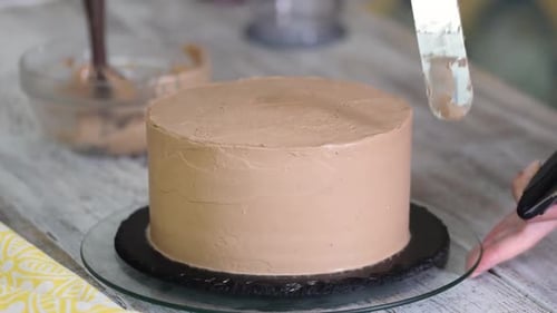 Person Decorating Cake with Chocolate Frosting