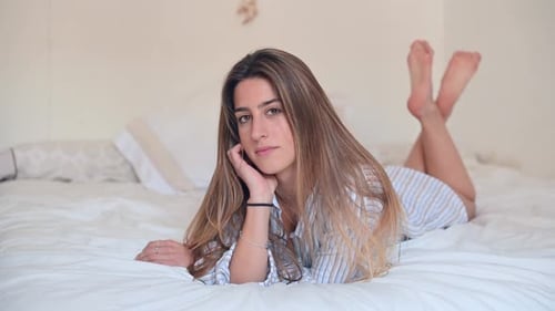 Smiling Woman Relaxing on a Bed Indoors