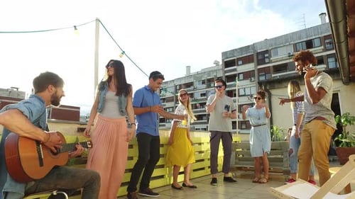 Friends Celebrating with Music on City Rooftop