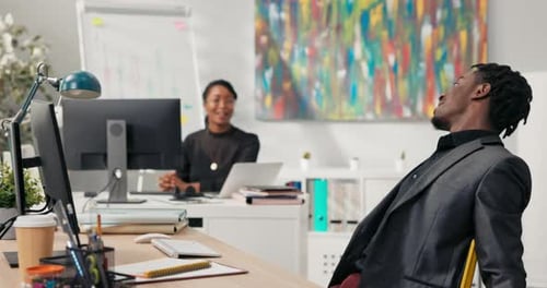 Des collègues à la peau foncée sont assis intensément dans le bureau de l'entreprise devant des ordinateurs
