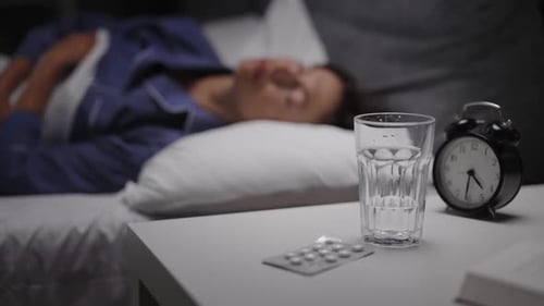 Woman Sleeping with Pills and Water on Nightstand