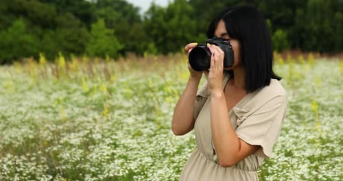 Female photographer take photo outdoors on flower field landscape holding a camera