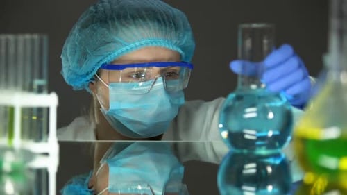 Scientist Holding Blue Chemical Flask in Lab