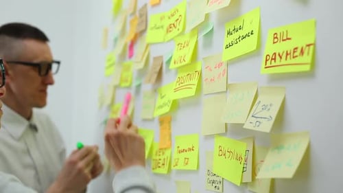 Ein Team von Geschäftsleuten schreibt Ideen und Entwicklungen auf Stickern auf einem Whiteboard auf. Brainstorming.