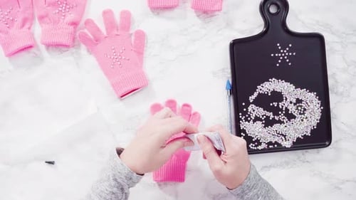 Flache Lage. Rosafarbene Strass-Handschuhe für Kinder mit Schneeflockenform.