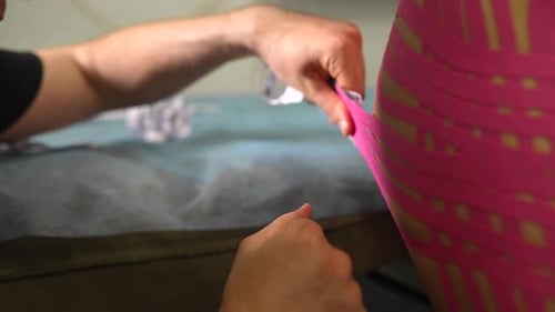 Fisioterapeuta aplicando cinta de kinesio en una paciente femenina