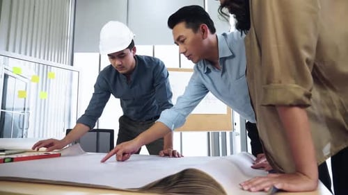 Team of young Asian architects and engineer discussing on construction site.