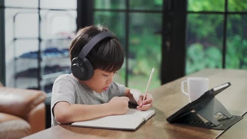 Homeschool Asian little young boy learning online class from school teacher by digital remote.