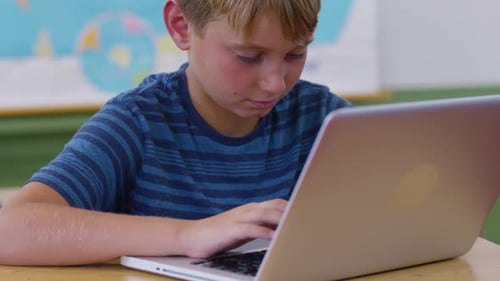 Boy in school classroom using laptop computer