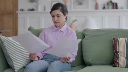 Young Adult Reading Documents on a Couch