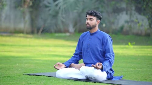 Man Meditating Peacefully on Lawn in Lotus Position