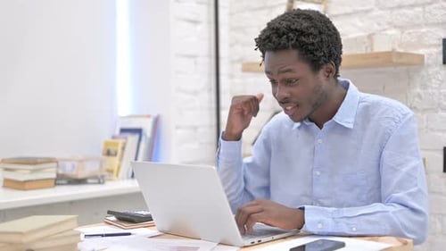 Young Man Video Conferencing at Desk Using Laptop