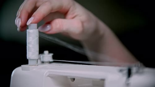 Hand der Näherin scrollt einen Fadenstrang