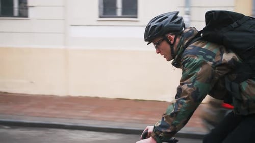 Young Hipster Man in Helmet Riding Fixed Gear Bicycle in the City During Autumn Morning Side View