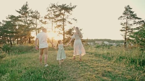 Young Married Couple with Cute Little Girl Spend Time Together Outdoors in the Forest