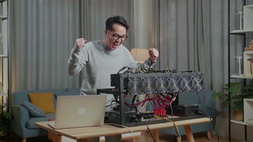 Happy Asian Man Celebrating Success With Mining Rig For Mining Cryptocurrency
