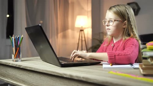 Cute School Girl Typing on Laptop at Home