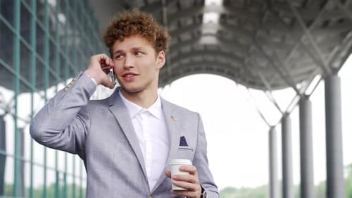 Young Man Talking on Phone With Coffee Outside