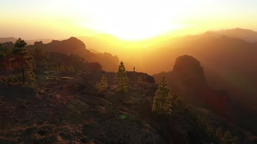 Man Looking At View As Sun Sets Over Misty Mountains