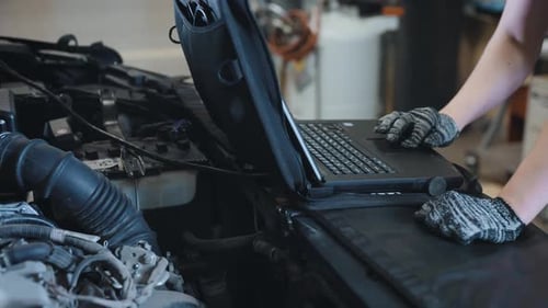 Mechanic Using Laptop to Diagnose Car Engine