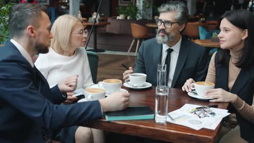 Cheerful Men and Women Business Partners in Suits Talking Smiling in Restaurant