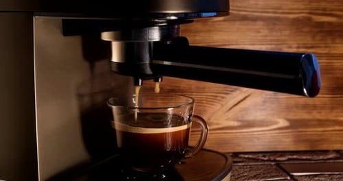 Pouring coffee stream from professional machine in cup
