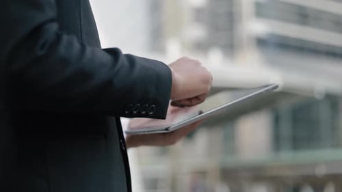 Adult Uses Tablet in City Setting