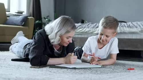 Woman and Child Drawing Together on Floor Indoors