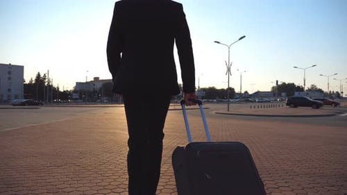 Person in Suit Walks with Suitcase in Urban Plaza