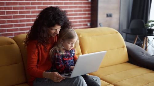 Mother and Daughter Siting on the Couch and Using Laptop