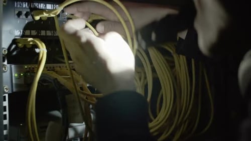 IT Technician Plugs Cables into Server Panel