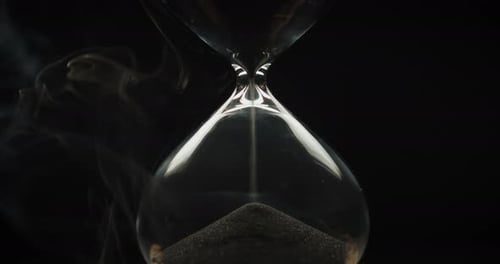 Hourglass with Falling Sand Against Dark Background