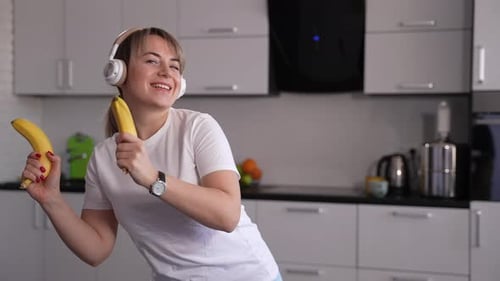 Woman Dances with Bananas in Kitchen, Listening Music