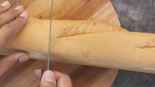 Cutting Fresh Baguette on Wooden Cutting Board