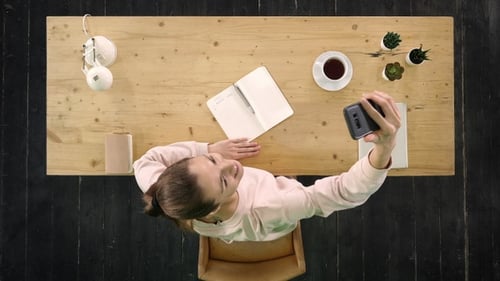 Woman Taking Selfie at Desk From Overhead Angle