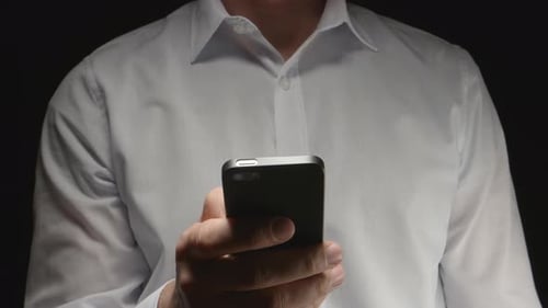 Man In White Shirt Holds A Smartphone By Hand And Touches On It