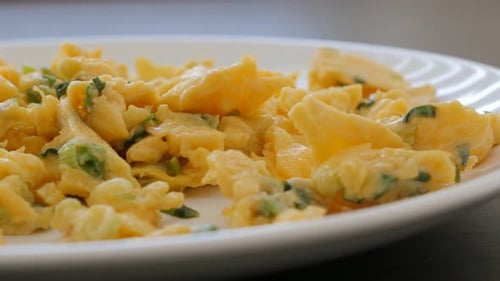 Omelette with green fresh scallion on ceramic plate slow panning 4K 2160p UHD footage - Beaten eggs