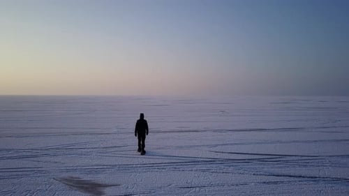 Drohnenansicht eines Mannes, der auf dem eisigen See läuft