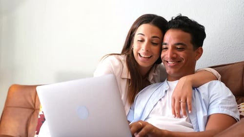 Smiling Couple Using Laptop Together on Couch